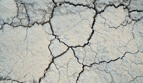 Above view of split soil in large parts. Concept of drought cracked texture background.